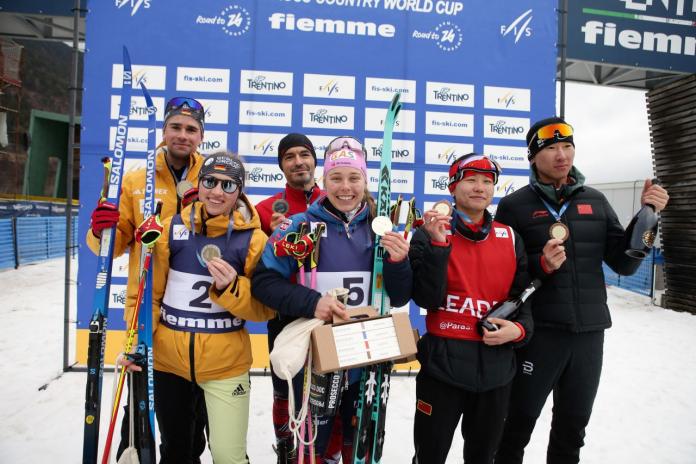 Three female skiers and their guides pose on the podium.